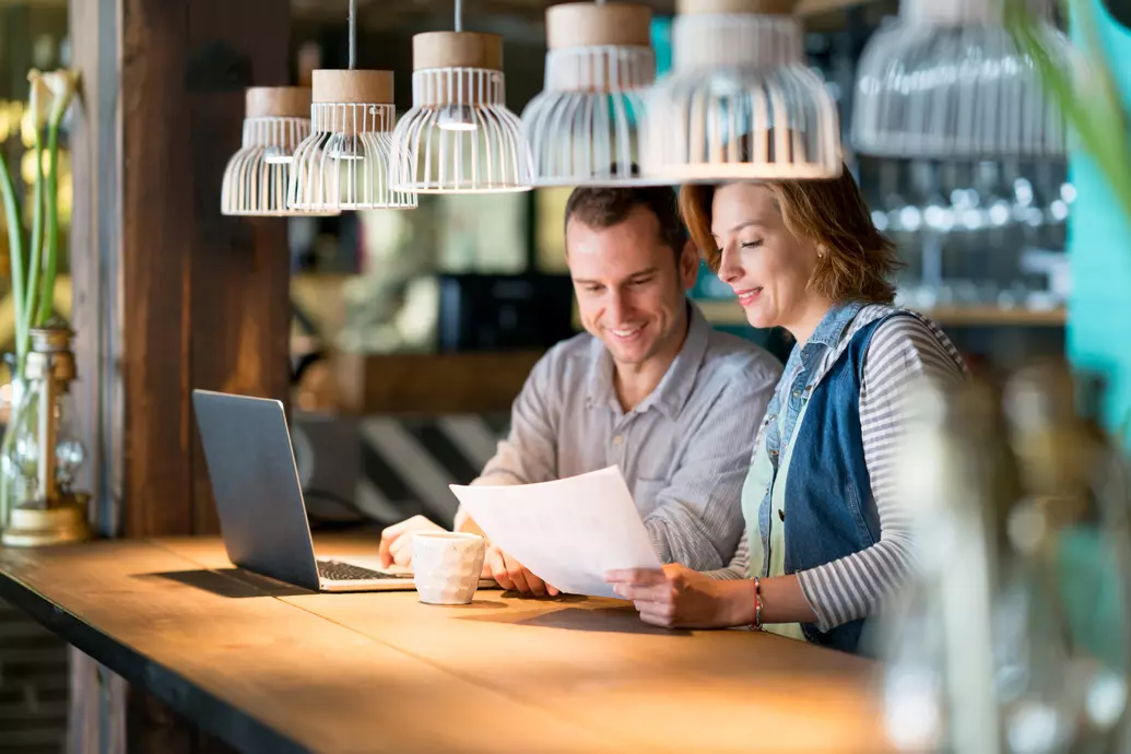 Homem e mulher felizes trabalhando em um cafe com um laptop