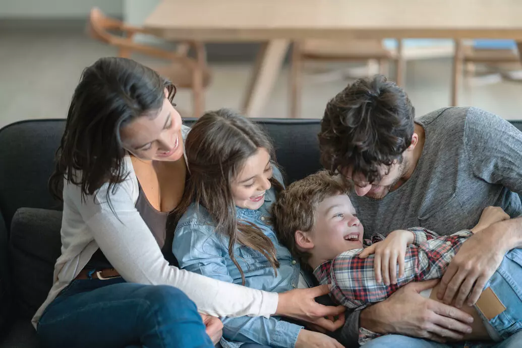Família feliz, abraçada, sentada no sofá