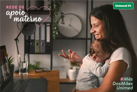 Mae e filho abraçados olhando para a tela do computador com um semblante feliz