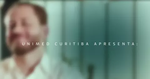 Trecho do videocase com a imagem de um personagem borrado com um texto sobreposto a frente escrito Unimed Curitiba apresenta
