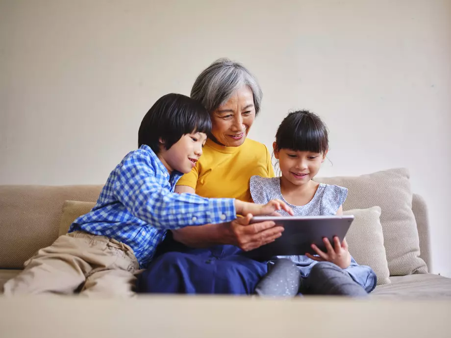 Avó e netos sentados no sofá, lendo algo no tablet