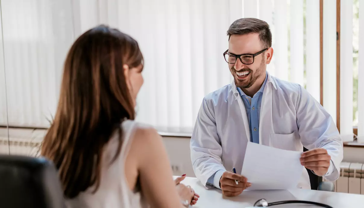 Médico feliz atendendo paciente mulher no consultório